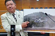 滋賀民報の写真パネルをしめし議会質問する後藤町議写真