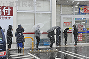 雪が降る中、薬局前で無料検査を待つ人たち写真