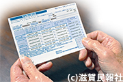 介護保険料などが記載された年金振込通知書を手にする高齢者写真